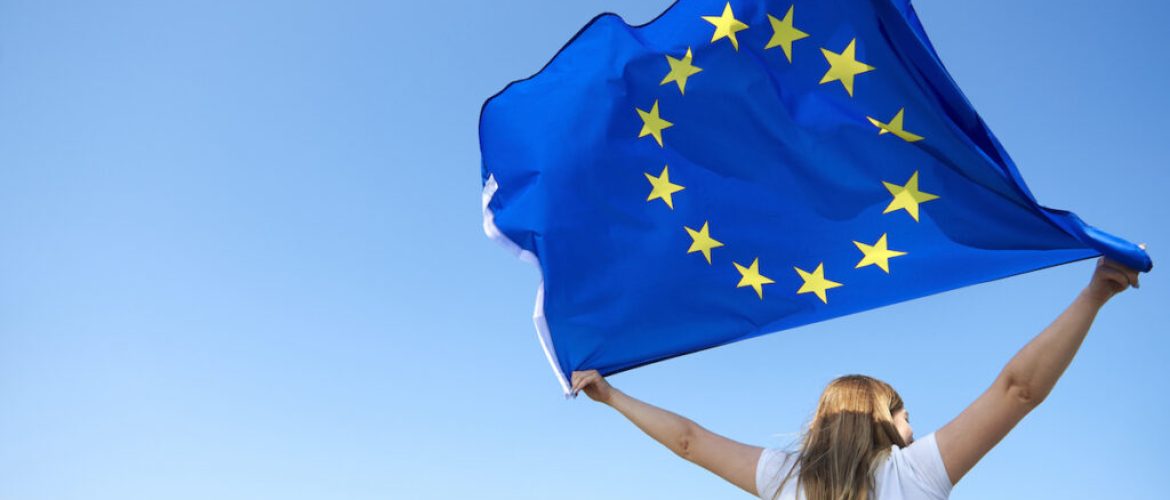 Rear view of young woman waving the European Union flag